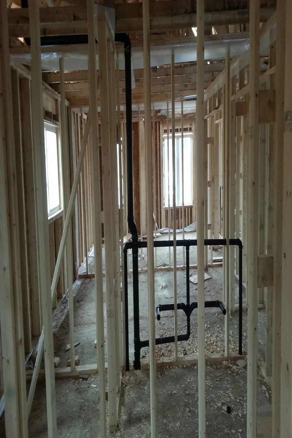 Black ABS drain and vent rough-in through new wall framing
