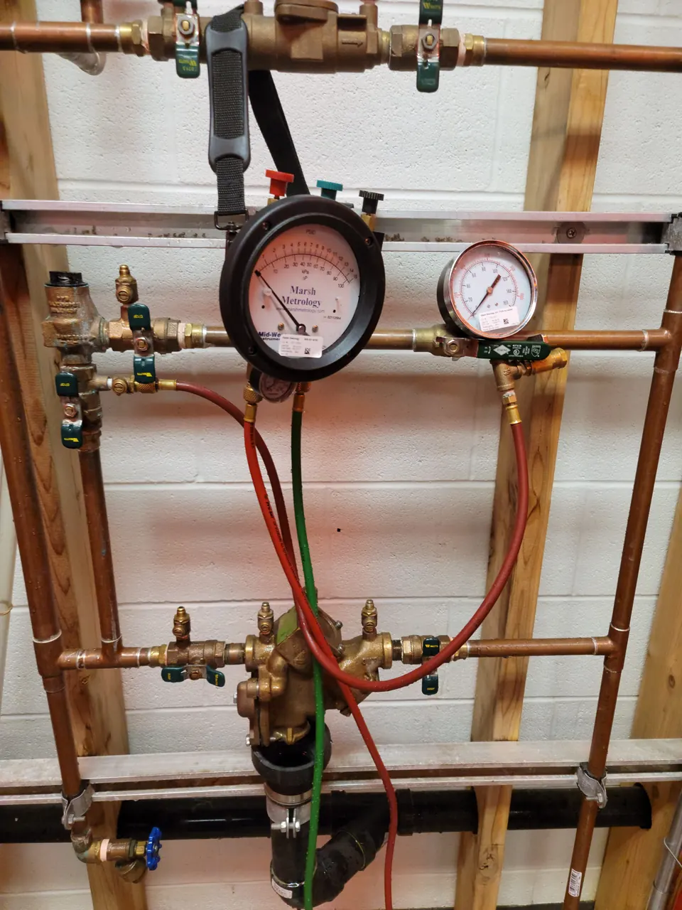 Backflow test kit gauges connected to a backflow preventer during an annual test