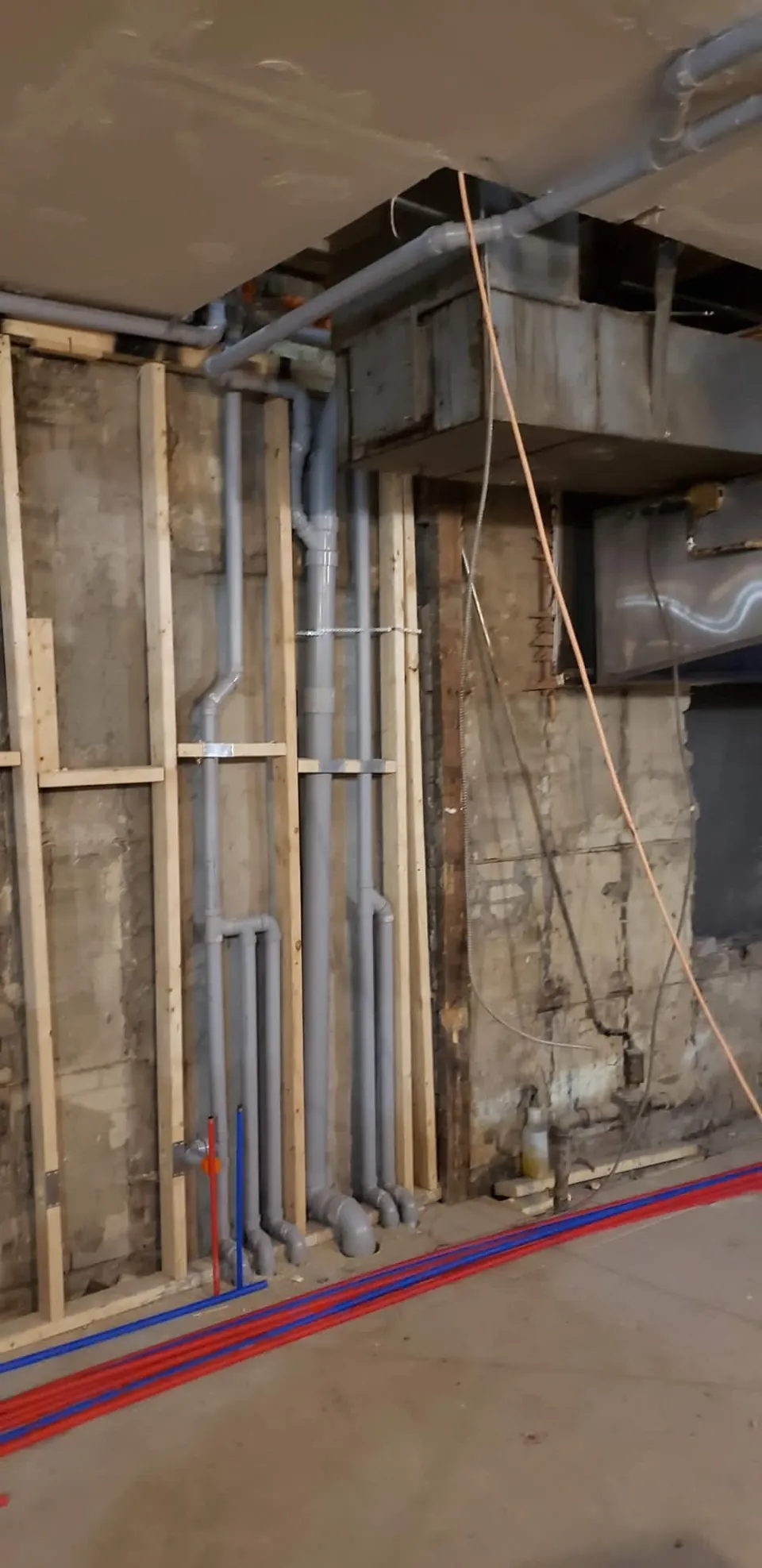 Basement rough-in with drain stacks and red and blue PEX water lines