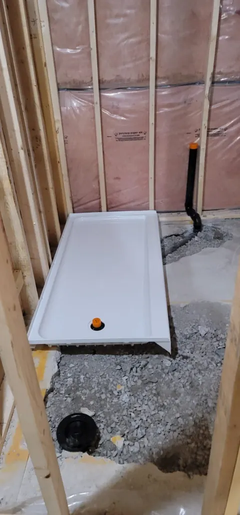 Shower base and drain roughed into a basement slab before framing is closed