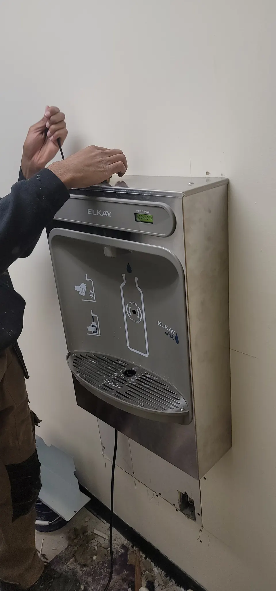 Plumber installing a wall-mounted bottle filling station