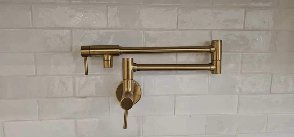 Brass wall-mounted pot filler over a kitchen range