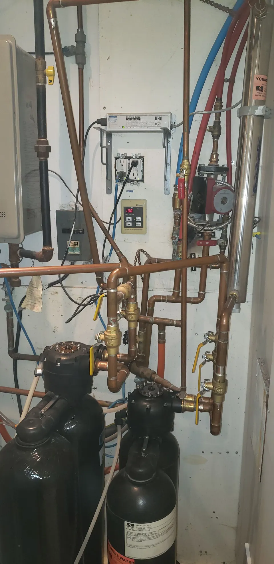 Copper piping with a circulator pump beside two water softener tanks