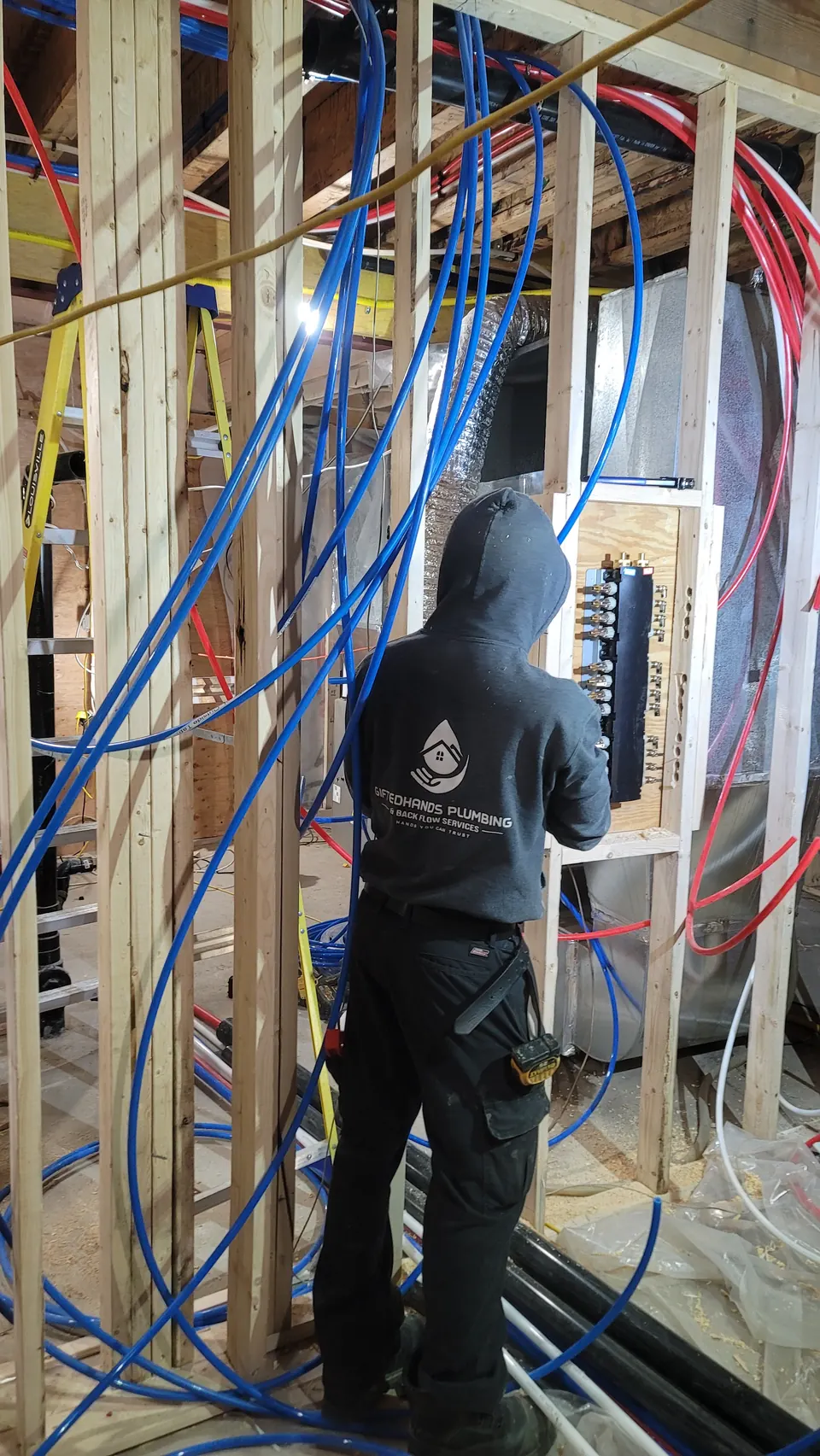 GiftedHands crew piping a PEX manifold wall in a multi-unit build