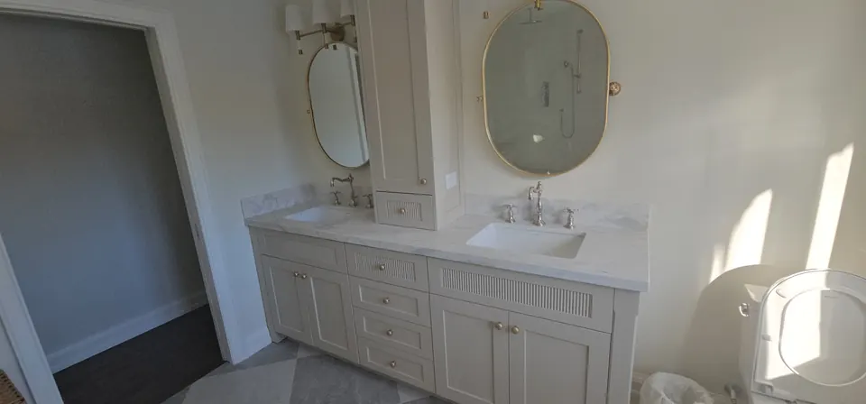 Double vanity with brass faucets and oval mirrors