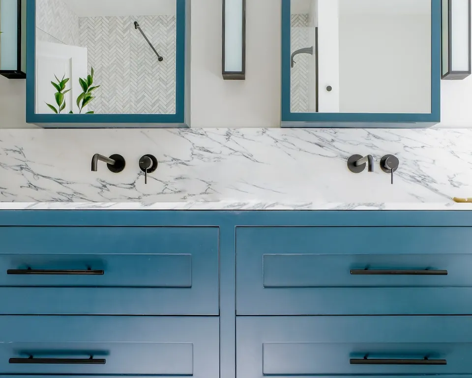 Double vanity with wall-mounted faucets and marble backsplash