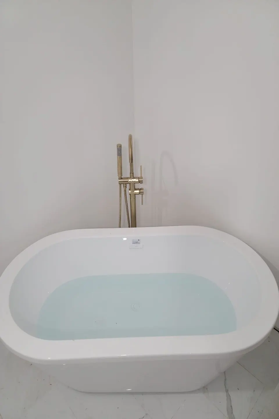 Freestanding soaker tub with a brass floor-mounted filler