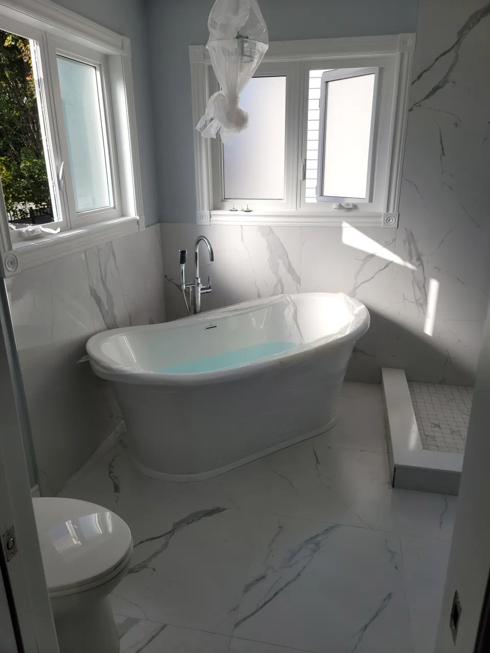 Freestanding tub in a marble-tiled bathroom