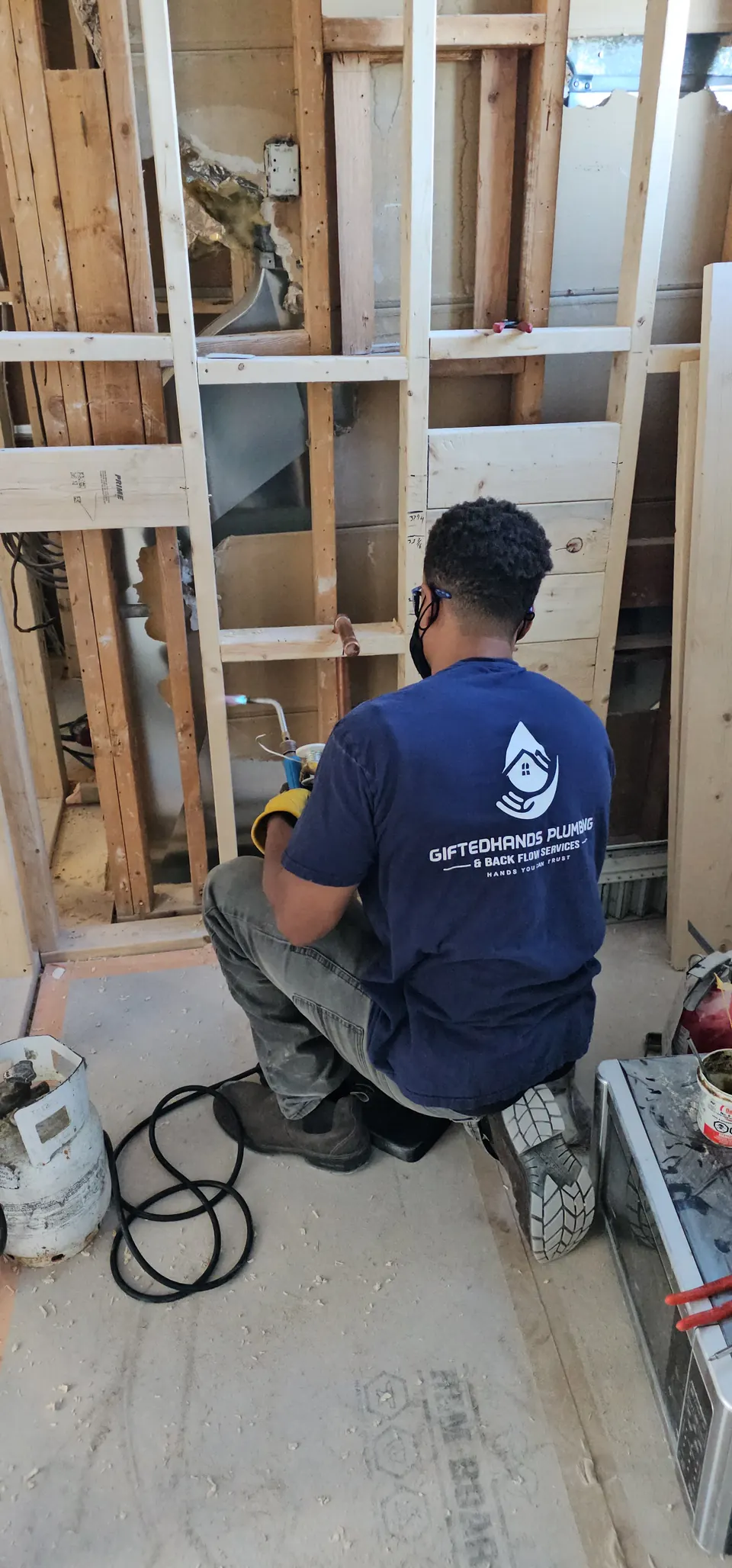 GiftedHands plumber in a branded shirt working on a rough-in