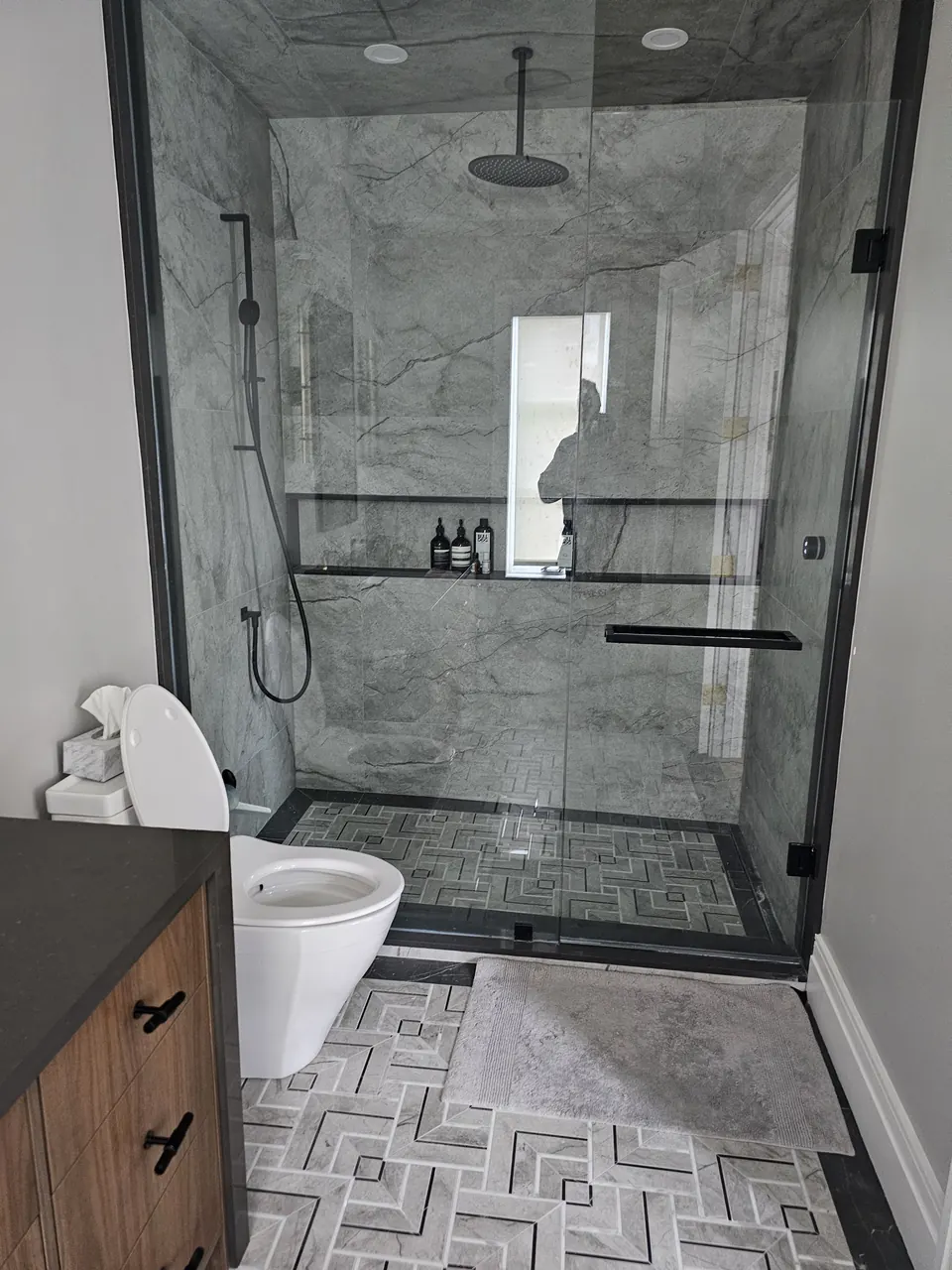 Glass-enclosed shower and wall-hung toilet after a renovation