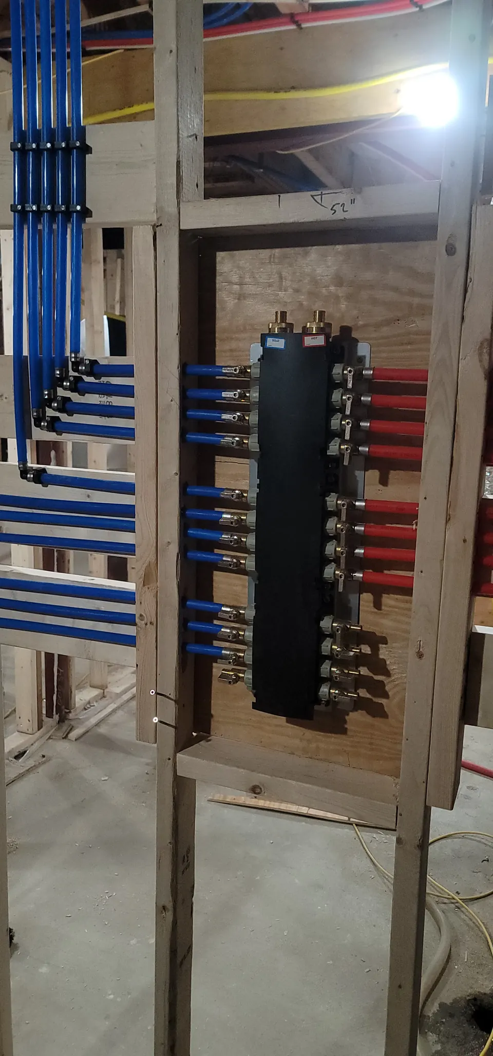 Home-run PEX manifold with red and blue lines in new framing