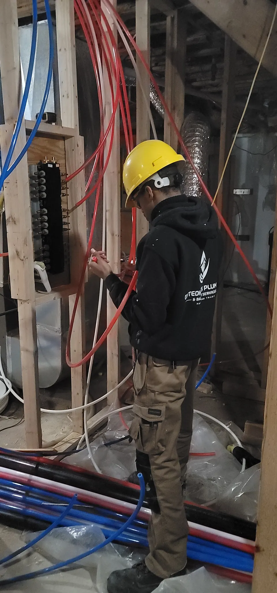 GiftedHands plumber in a hard hat roughing in a multi-unit building
