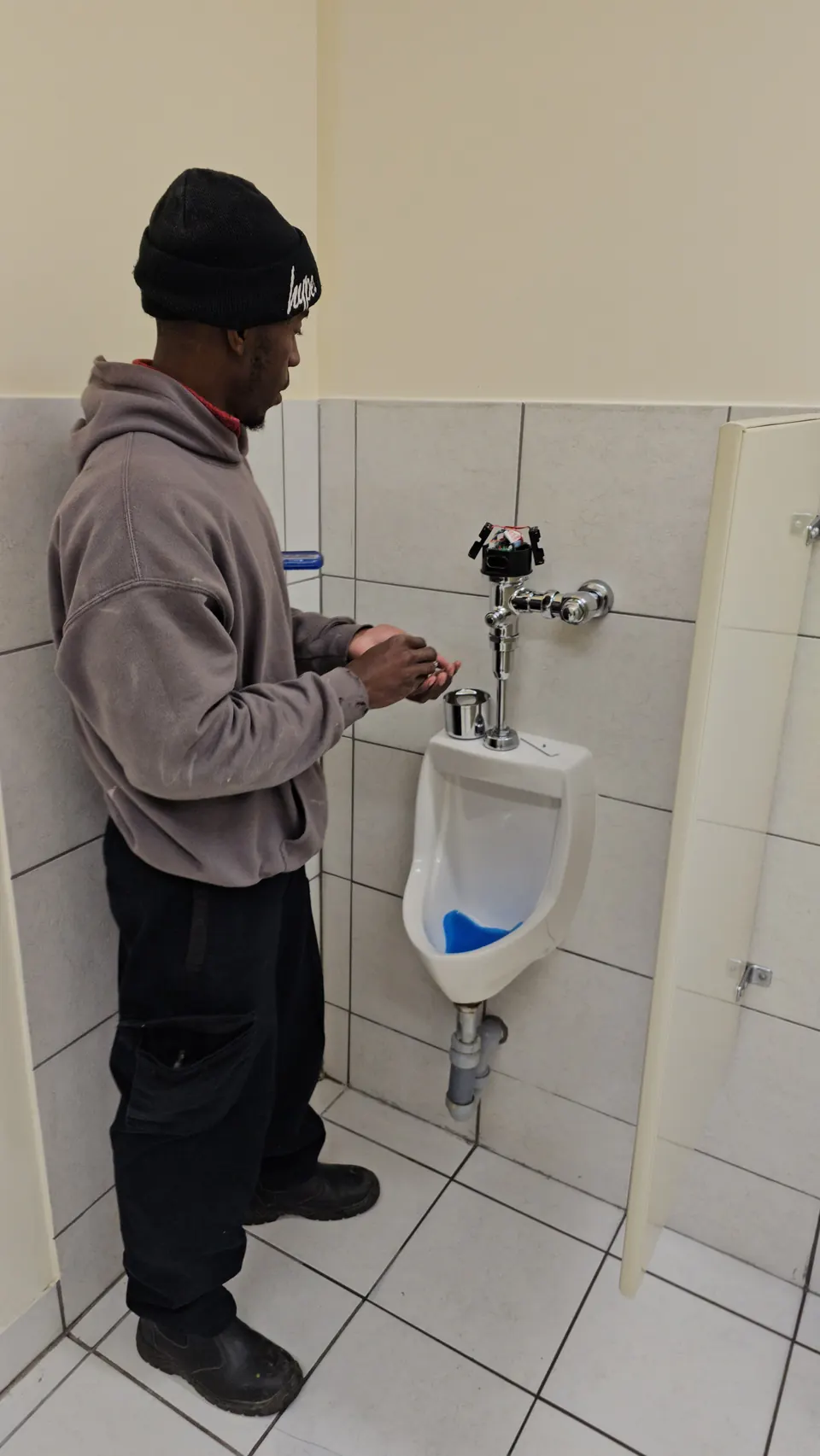 GiftedHands plumber installing a flush valve on a commercial urinal