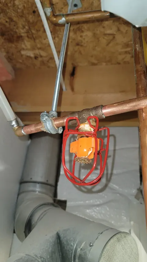 Fire sprinkler head on a copper water line below the ceiling joists