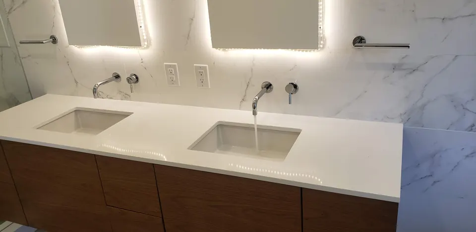 Vanity with a wall-mounted faucet and backlit mirror