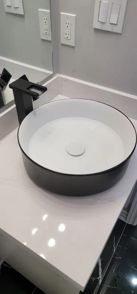 Round vessel sink with a tall black faucet on a quartz vanity