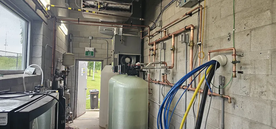 Water softener tank with copper distribution piping on a block wall